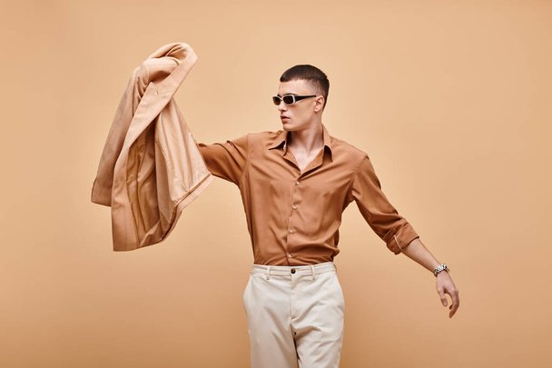 stock-photo-fashion-shot-man-beige-shirt-sunglasses-holding-jacket-hand-beige